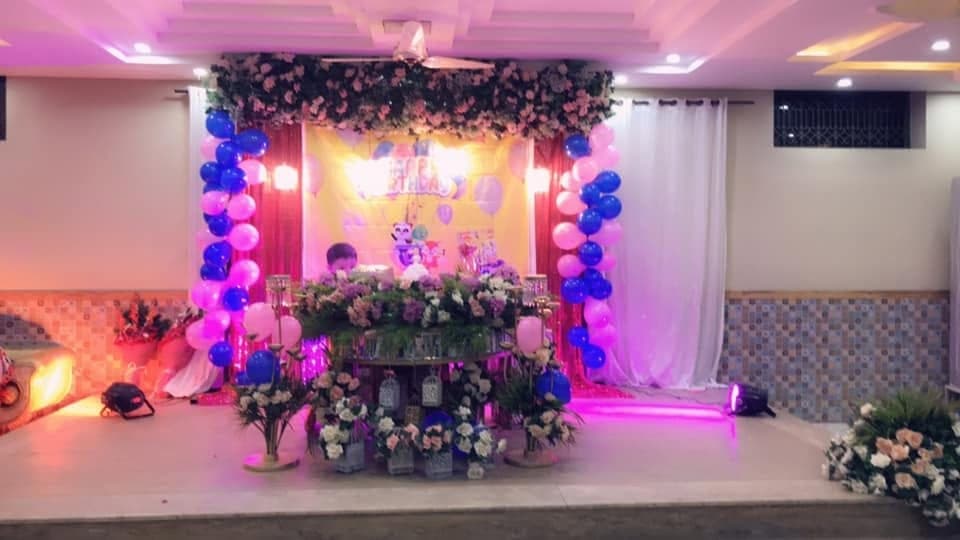 Birthday stage decorated with balloons, greenery and pink lighting