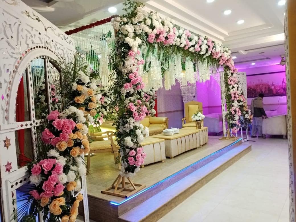 Carved white frame dressed with roses and trailing greenery beside the stage