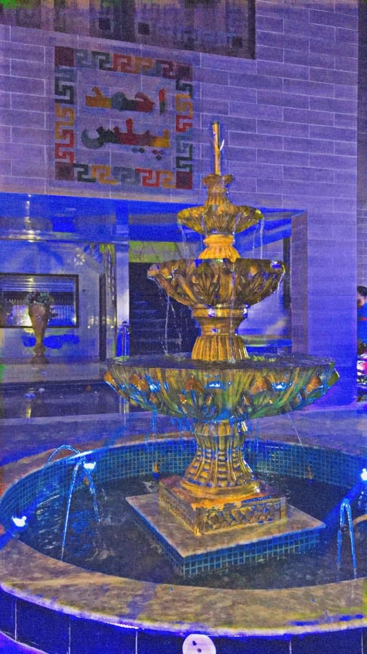 Tiered stone fountain in the courtyard at Ahmed Palace, lit blue after dark