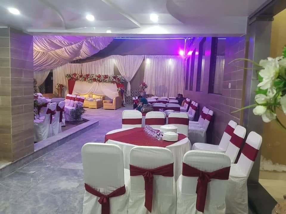 Round tables dressed in white and maroon linen, set for a walima reception