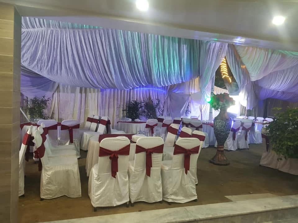 Marquee dining area with draped ceiling and rows of covered chairs with maroon sashes