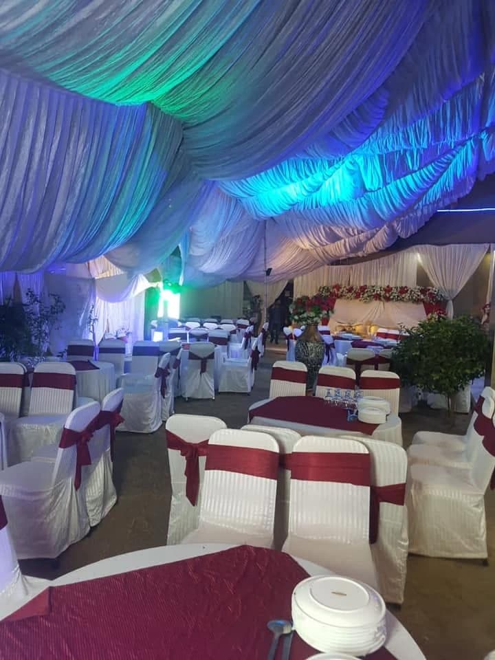 Round banquet tables laid with crockery under a draped marquee ceiling
