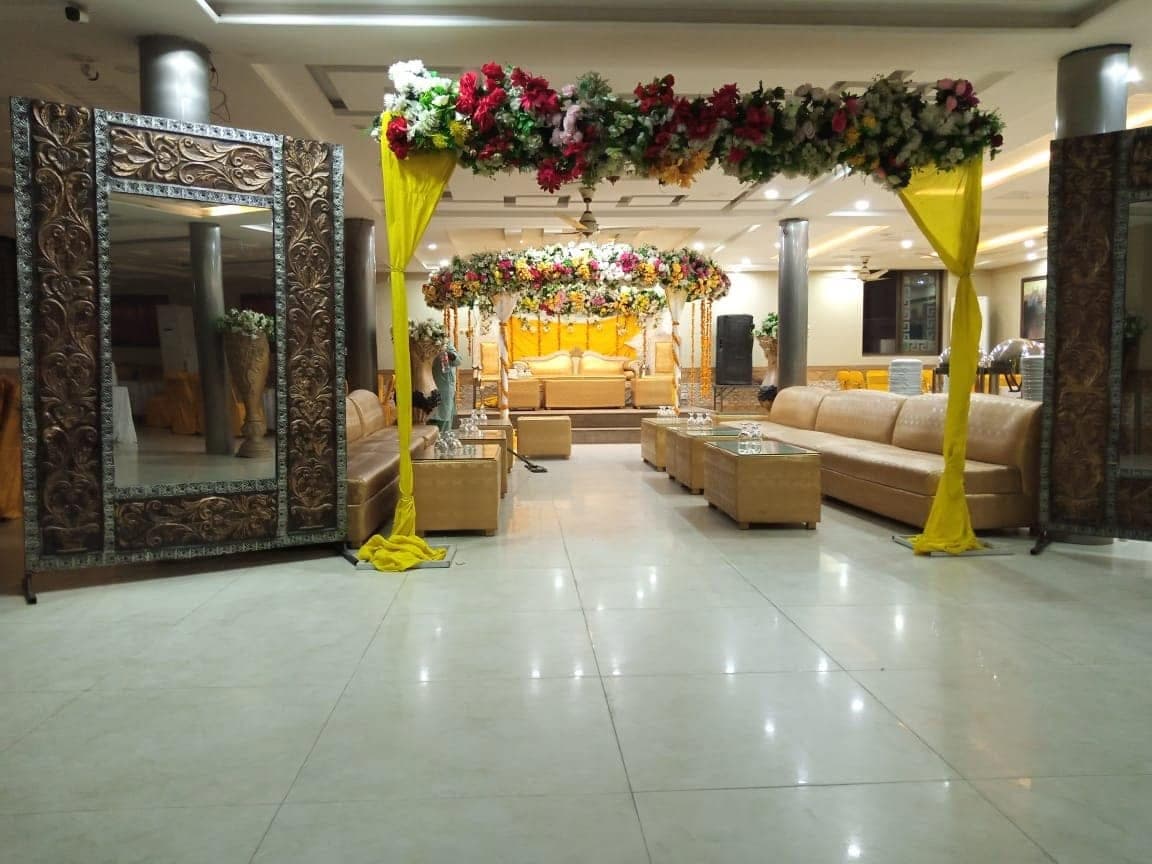Wide view of the Ahmed Palace banquet hall set with gold seating and floral entrance décor