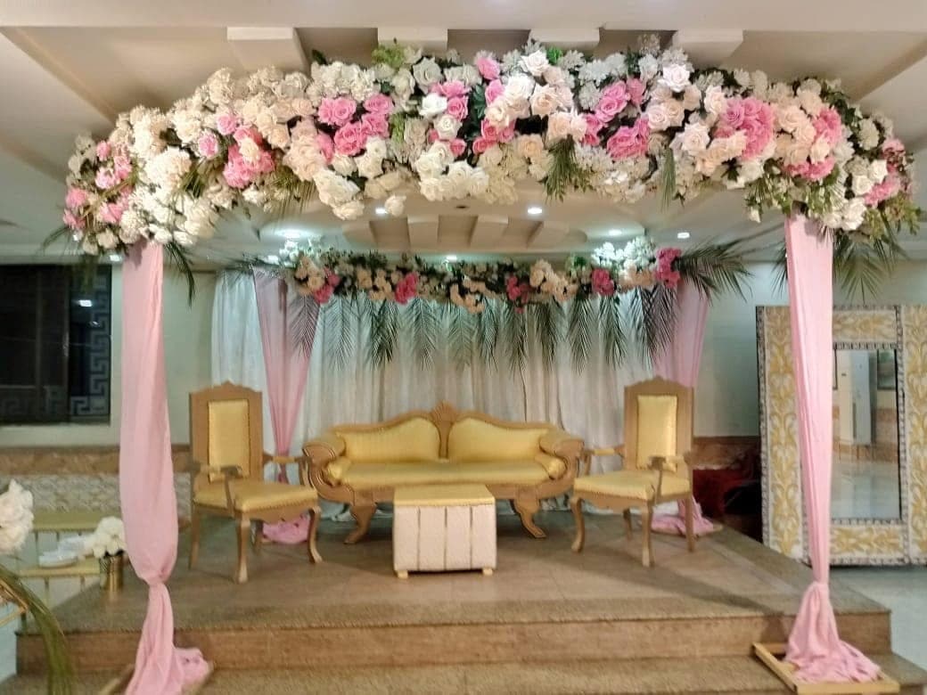 Bridal stage with blush drapery, gold seating and a canopy of white and pink flowers