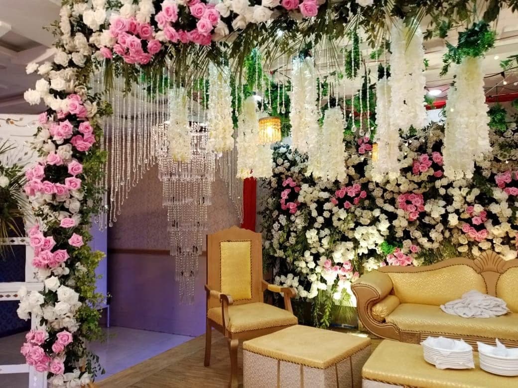 Gold sofa framed by a canopy of hanging jasmine garlands and roses on the Ahmed Palace stage