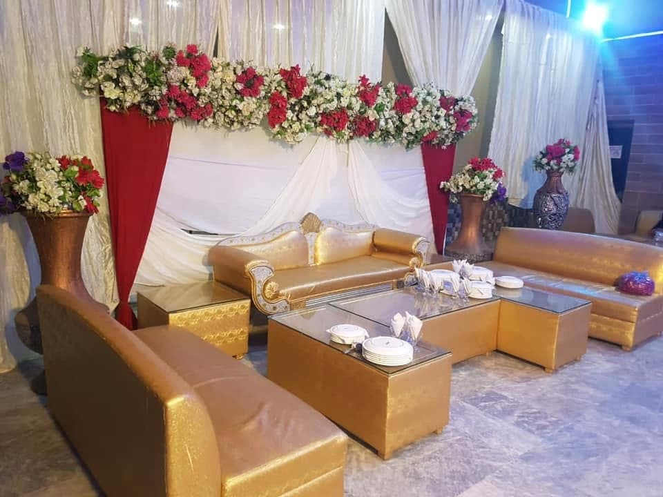 Gold lounge seating on the stage beneath a red and white floral backdrop at Ahmed Palace