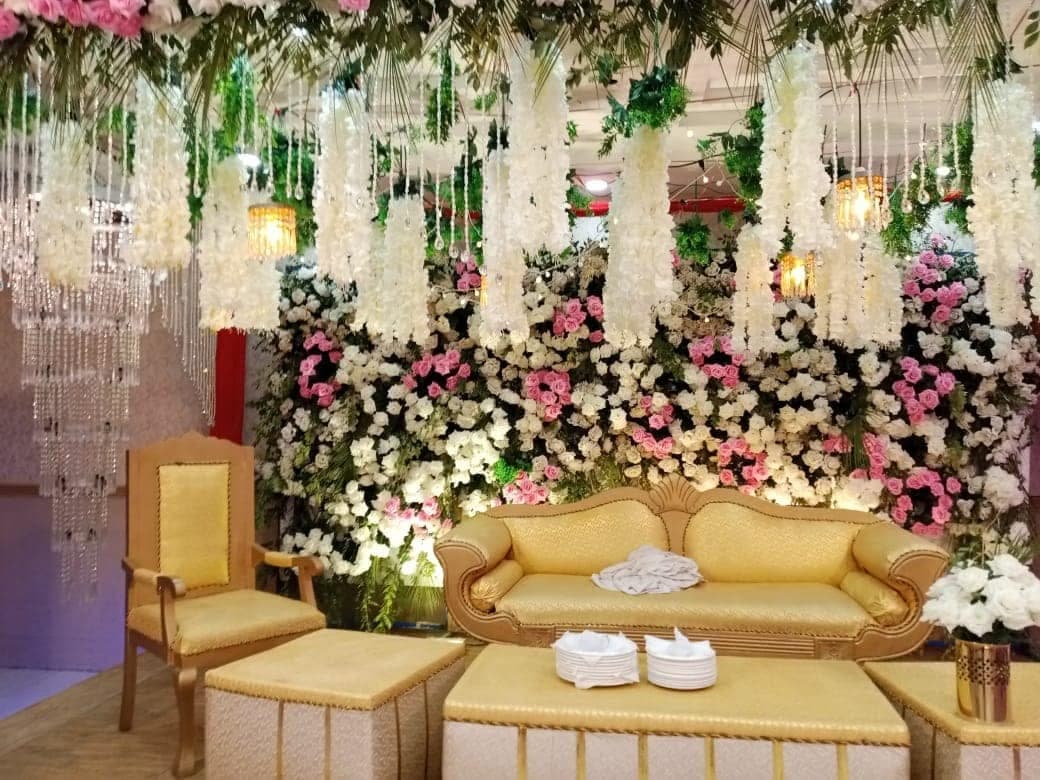 Gilded wedding sofa set against cascading white floral garlands and crystal strands at Ahmed Palace
