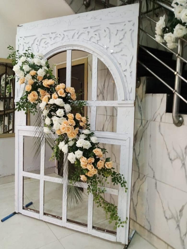 Carved white arch framed with peach and cream floral arrangements in the entrance hall at Ahmed Palace