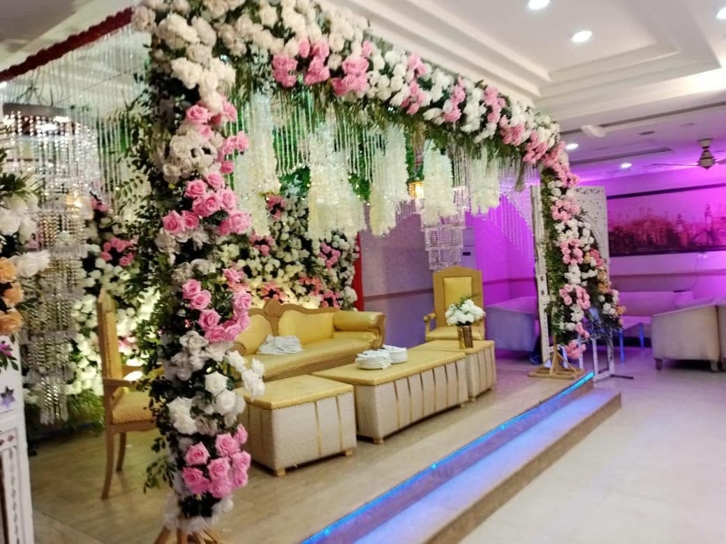 Floral archway over the bridal stage, dressed in white and blush roses, at Ahmed Palace Lahore